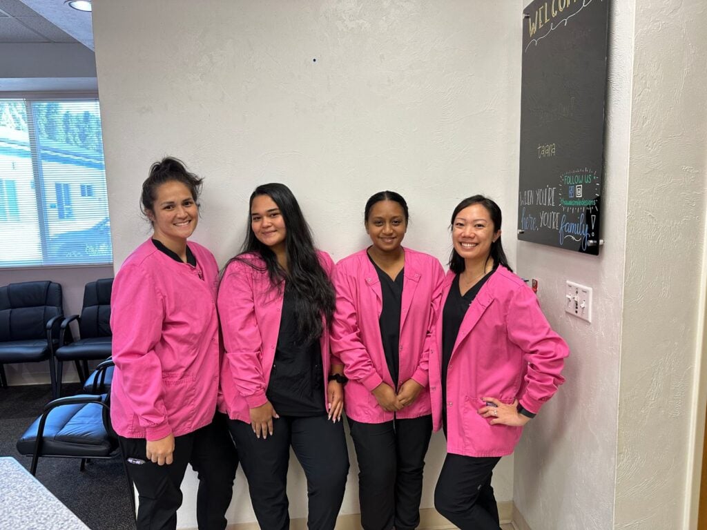 Four team members wearing pink jackets and posing